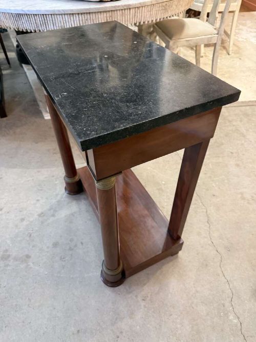 A small late nineteenth-century French Empire style mahogany console table featuring a black marble top, cylindrical column legs with metallic accents, a single frieze drawer with a brass laurel mount, and a lower shelf. View VI