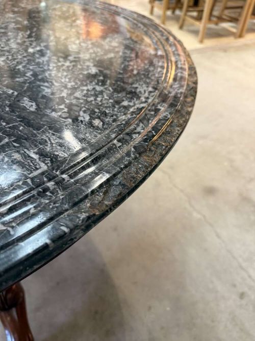 A 19th-century French circular gueridon table featuring a dark grey veined marble top resting on a carved mahogany pedestal base with carved feet. View IV