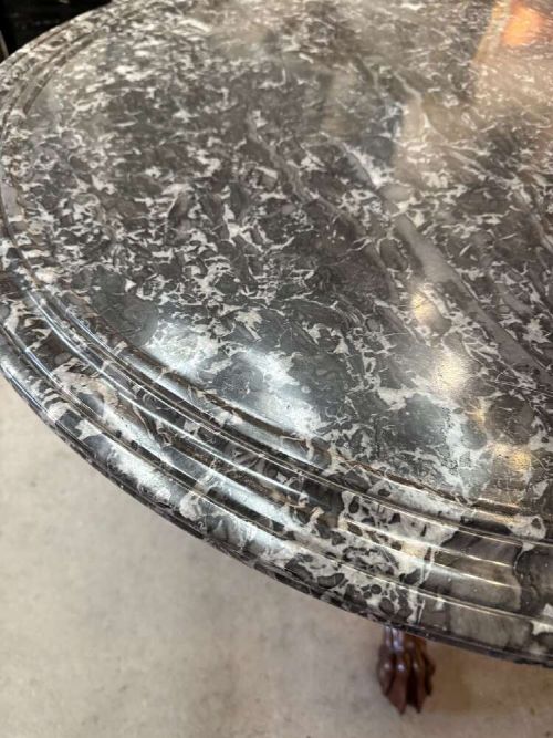 A 19th-century French circular gueridon table featuring a dark grey veined marble top resting on a carved mahogany pedestal base with carved feet. View V
