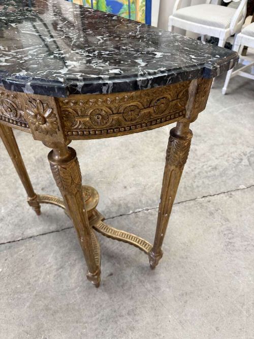 A late 19th-century French Louis XVI style demi-lune console table featuring a dark marble top, carved gilded legs, and a central urn finial. View III