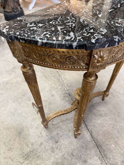 A late 19th-century French Louis XVI style demi-lune console table featuring a dark marble top, carved gilded legs, and a central urn finial. View V