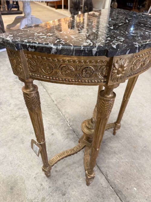 A late 19th-century French Louis XVI style demi-lune console table featuring a dark marble top, carved gilded legs, and a central urn finial. View VI
