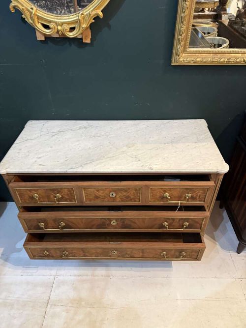 A nineteenth-century Louis XVI style scrubbed mahogany commode featuring three drawers, brass handles, keyhole escutcheons, turned tapered legs, and a fitted white marble top. View VI