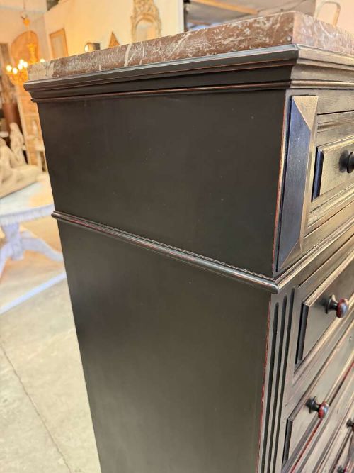 A tall narrow black ebonised chest of drawers featuring seven moulded drawers, turned wooden knobs, and a dark marble top. View X