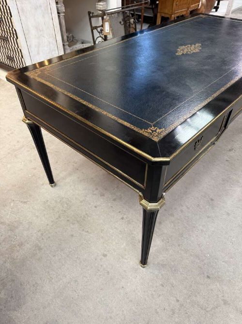 A 19th-century French ebonised writing desk with a black leather inset top, gilt-tooled border, three frieze drawers, brass mounts, and tapered fluted legs. View II