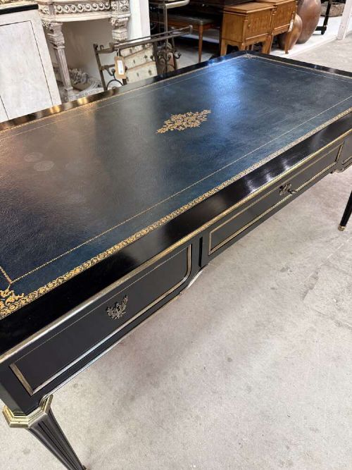 A 19th-century French ebonised writing desk with a black leather inset top, gilt-tooled border, three frieze drawers, brass mounts, and tapered fluted legs. View III