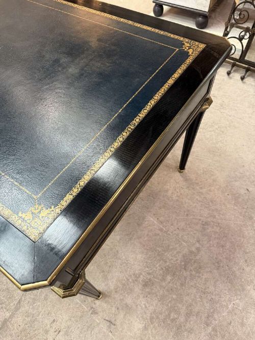 A 19th-century French ebonised writing desk with a black leather inset top, gilt-tooled border, three frieze drawers, brass mounts, and tapered fluted legs. View VIII