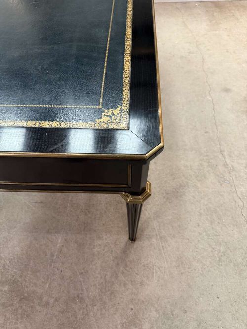 A 19th-century French ebonised writing desk with a black leather inset top, gilt-tooled border, three frieze drawers, brass mounts, and tapered fluted legs. View IX