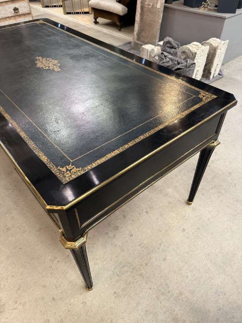 A 19th-century French ebonised writing desk with a black leather inset top, gilt-tooled border, three frieze drawers, brass mounts, and tapered fluted legs. View XI