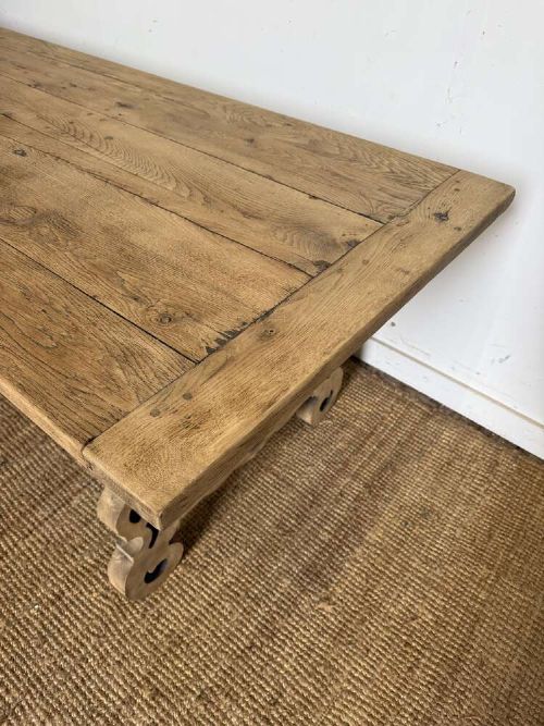 A long scrubbed oak refectory table with carved trestle legs connected by a central curved wrought iron scroll stretcher. View II