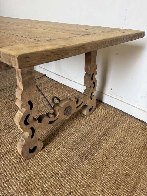 A long scrubbed oak refectory table with carved trestle legs connected by a central curved wrought iron scroll stretcher. View VII