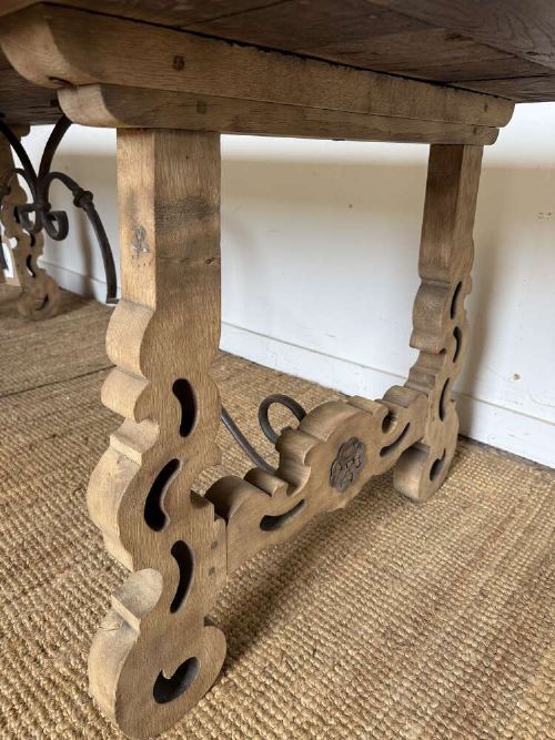 A long scrubbed oak refectory table with carved trestle legs connected by a central curved wrought iron scroll stretcher. View VIII