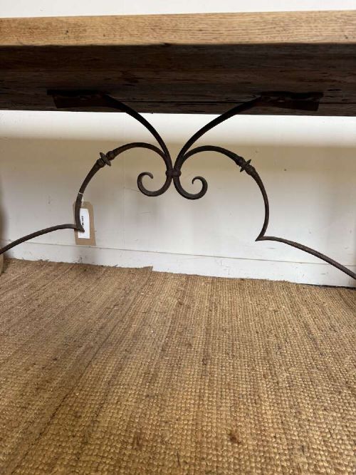 A long scrubbed oak refectory table with carved trestle legs connected by a central curved wrought iron scroll stretcher. View XI