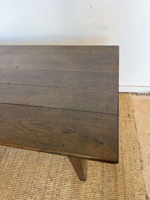 A long dark oak French farmhouse dining table featuring a plank top surface and four tapered square legs. View III