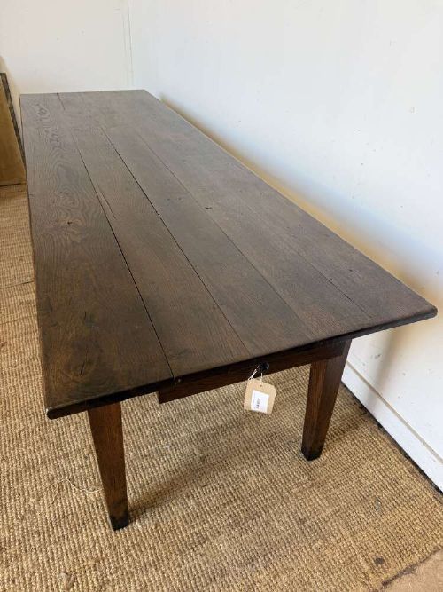 A long dark oak French farmhouse dining table featuring a plank top surface and four tapered square legs. View XII