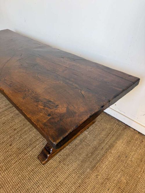An early 20th century French dark oak refectory table featuring a single plank top supported by a pegged trestle base with a central stretcher. View III