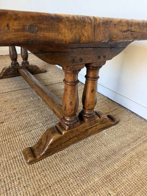 An early 20th-century oak refectory dining table featuring a rectangular framed plank top supported by turned legs on a trestle base with a stretcher rail. View V