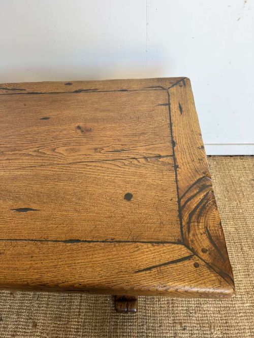 An early 20th-century oak refectory dining table featuring a rectangular framed plank top supported by turned legs on a trestle base with a stretcher rail. View VI