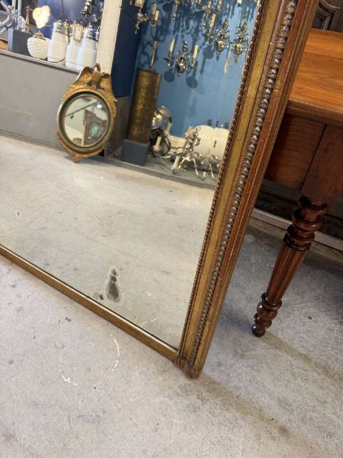 A large 19th-century French Louis Philippe rectangular mirror featuring a gilded frame with rounded top corners, beaded inner moulding, and an ornate floral crest at the top centre. View IV