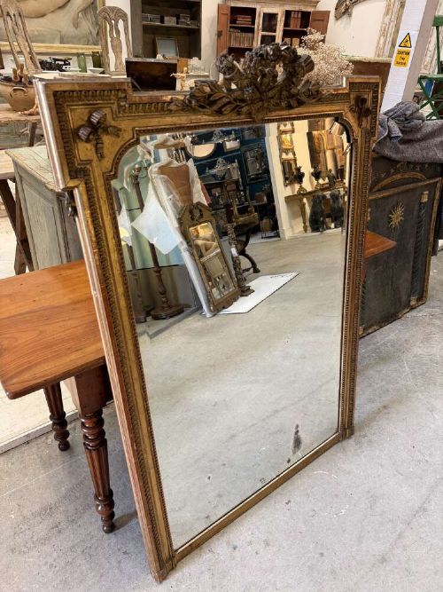 A large 19th-century French Louis Philippe rectangular mirror featuring a gilded frame with rounded top corners, beaded inner moulding, and an ornate floral crest at the top centre. View V
