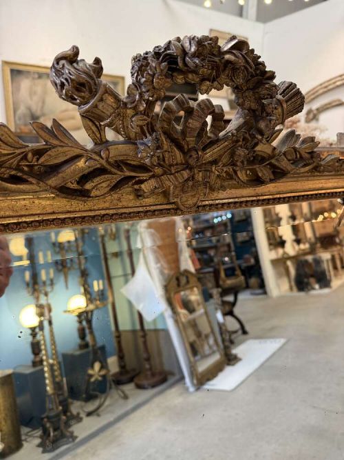 A large 19th-century French Louis Philippe rectangular mirror featuring a gilded frame with rounded top corners, beaded inner moulding, and an ornate floral crest at the top centre. View VII