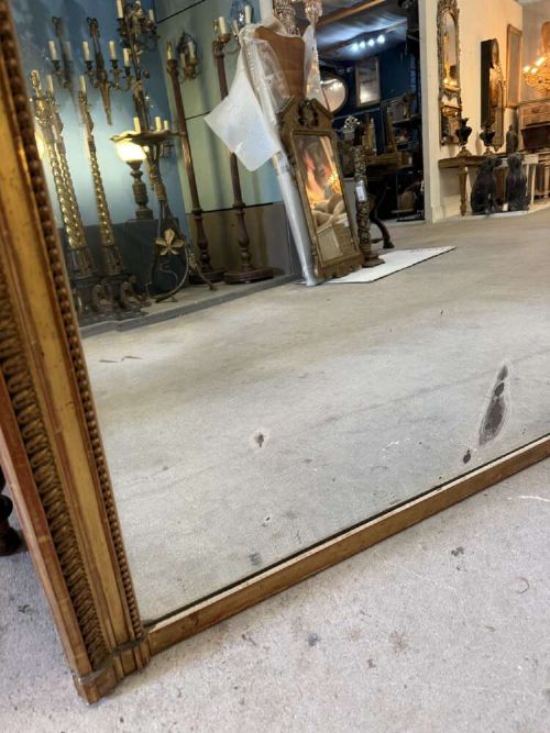 A large 19th-century French Louis Philippe rectangular mirror featuring a gilded frame with rounded top corners, beaded inner moulding, and an ornate floral crest at the top centre. View VIII