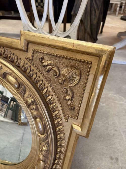 A square carved giltwood frame with detailed corner spandrels housing a central round convex glass mirror. View II