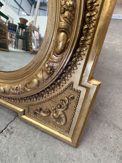 A square carved giltwood frame with detailed corner spandrels housing a central round convex glass mirror. View IV