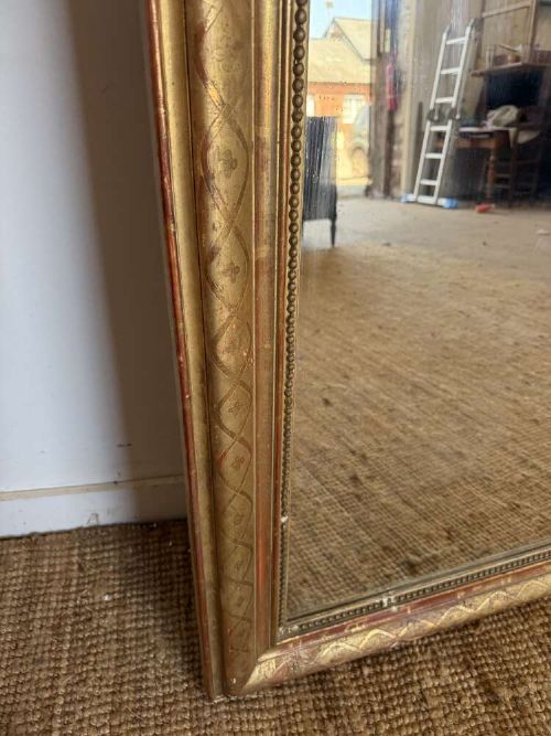 A late nineteenth-century French rectangular wall mirror featuring rounded upper corners, an incised gold gilt frame, and a beaded inner border. View X