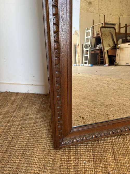 A late 19th-century French carved oak wall mirror with rounded top corners and detailed carved egg and dart moulding along the frame. View V