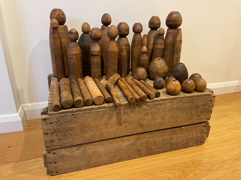 A collection of assorted vintage wooden plumbers turpins, dressers, and cylindrical tools arranged on a wooden surface.