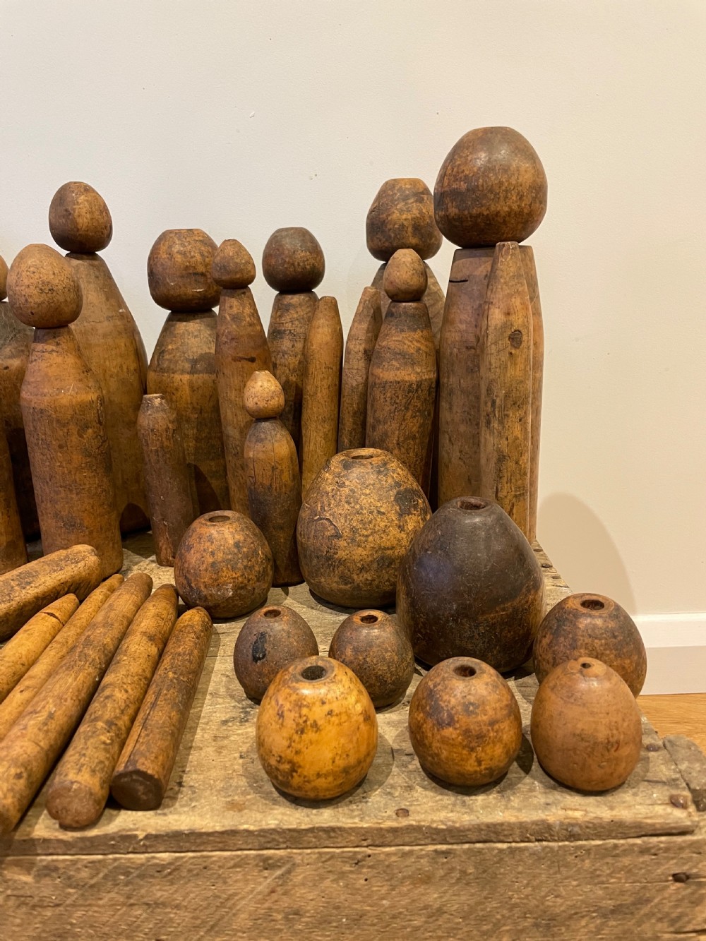 A collection of assorted vintage wooden plumbers turpins, dressers, and cylindrical tools arranged on a wooden surface. View II