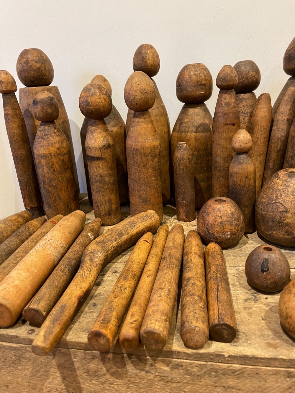 A collection of assorted vintage wooden plumbers turpins, dressers, and cylindrical tools arranged on a wooden surface. View III