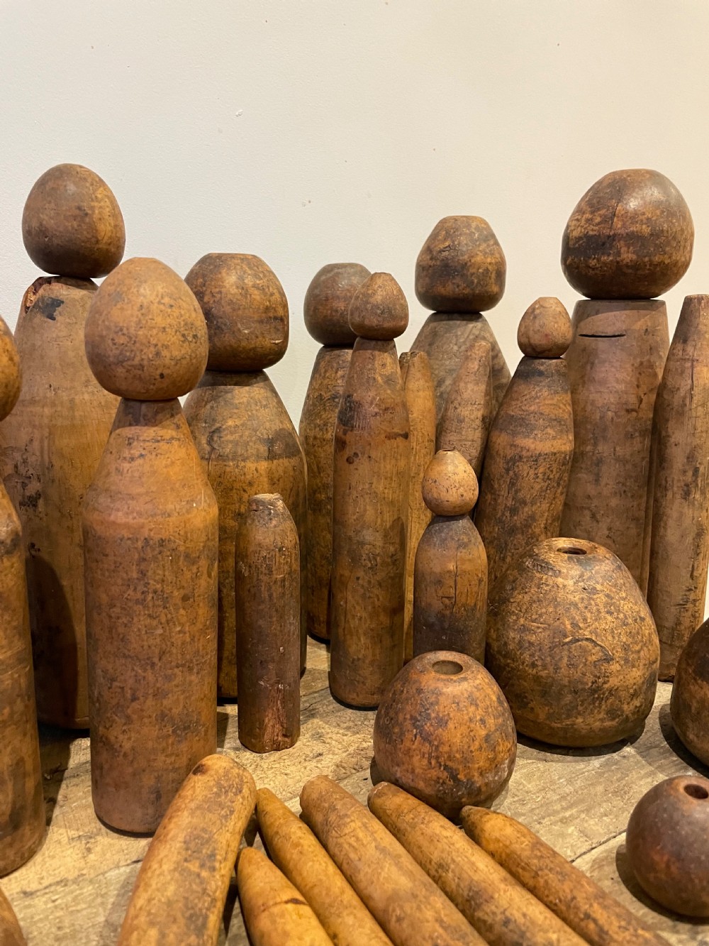 A collection of assorted vintage wooden plumbers turpins, dressers, and cylindrical tools arranged on a wooden surface. View V