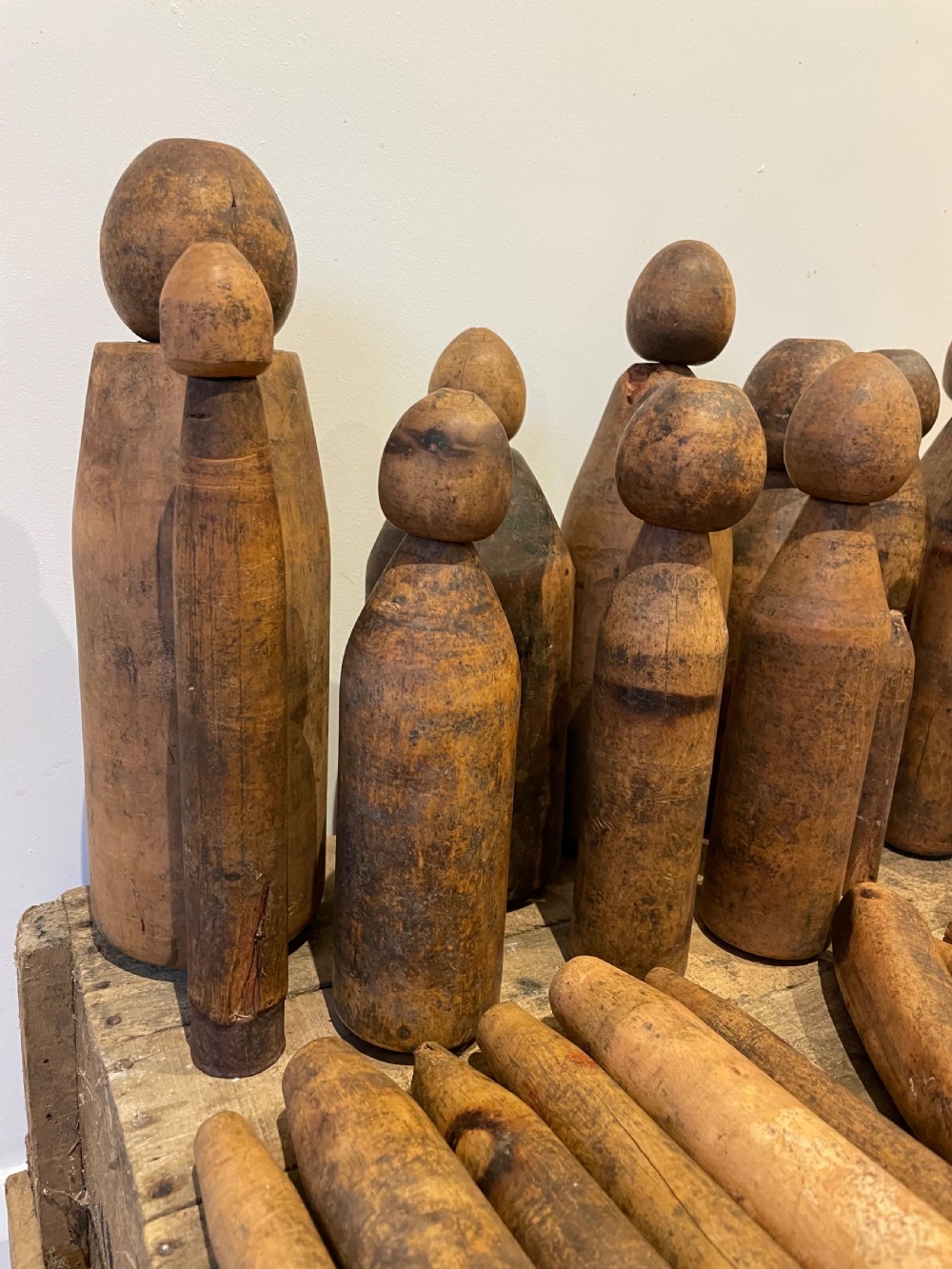 A collection of assorted vintage wooden plumbers turpins, dressers, and cylindrical tools arranged on a wooden surface. View VI