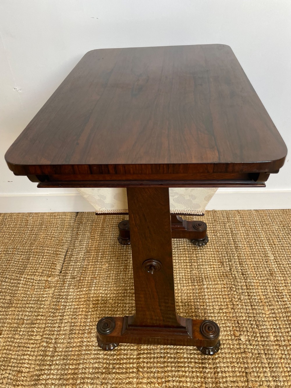 A Victorian rosewood work table featuring a single drawer with a brass ring handle, carved side brackets, and an upholstered fabric well beneath. View V