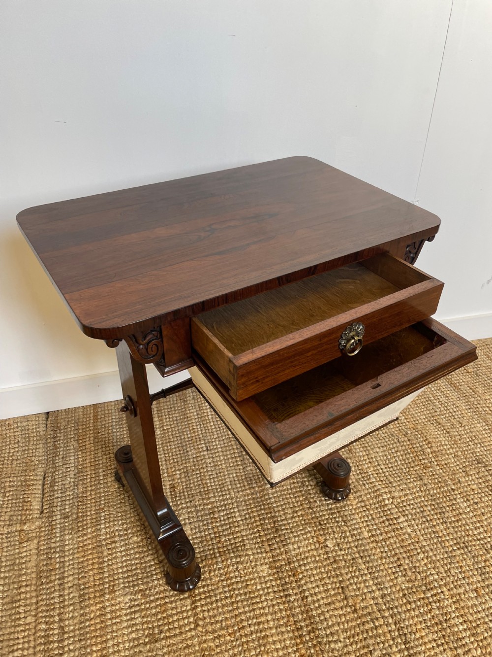 A Victorian rosewood work table featuring a single drawer with a brass ring handle, carved side brackets, and an upholstered fabric well beneath. View VII