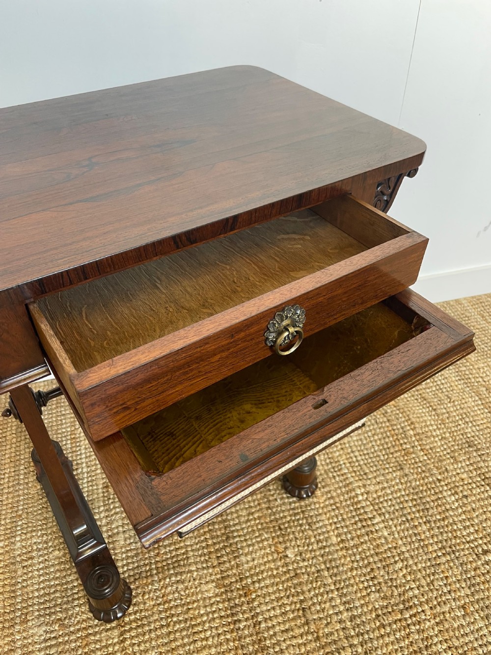 A Victorian rosewood work table featuring a single drawer with a brass ring handle, carved side brackets, and an upholstered fabric well beneath. View VIII