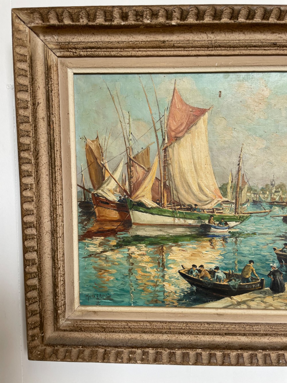 An oil painting on canvas depicting traditional fishing boats docked in a harbour alongside figures on a stone quay, enclosed in a carved wooden frame. View III