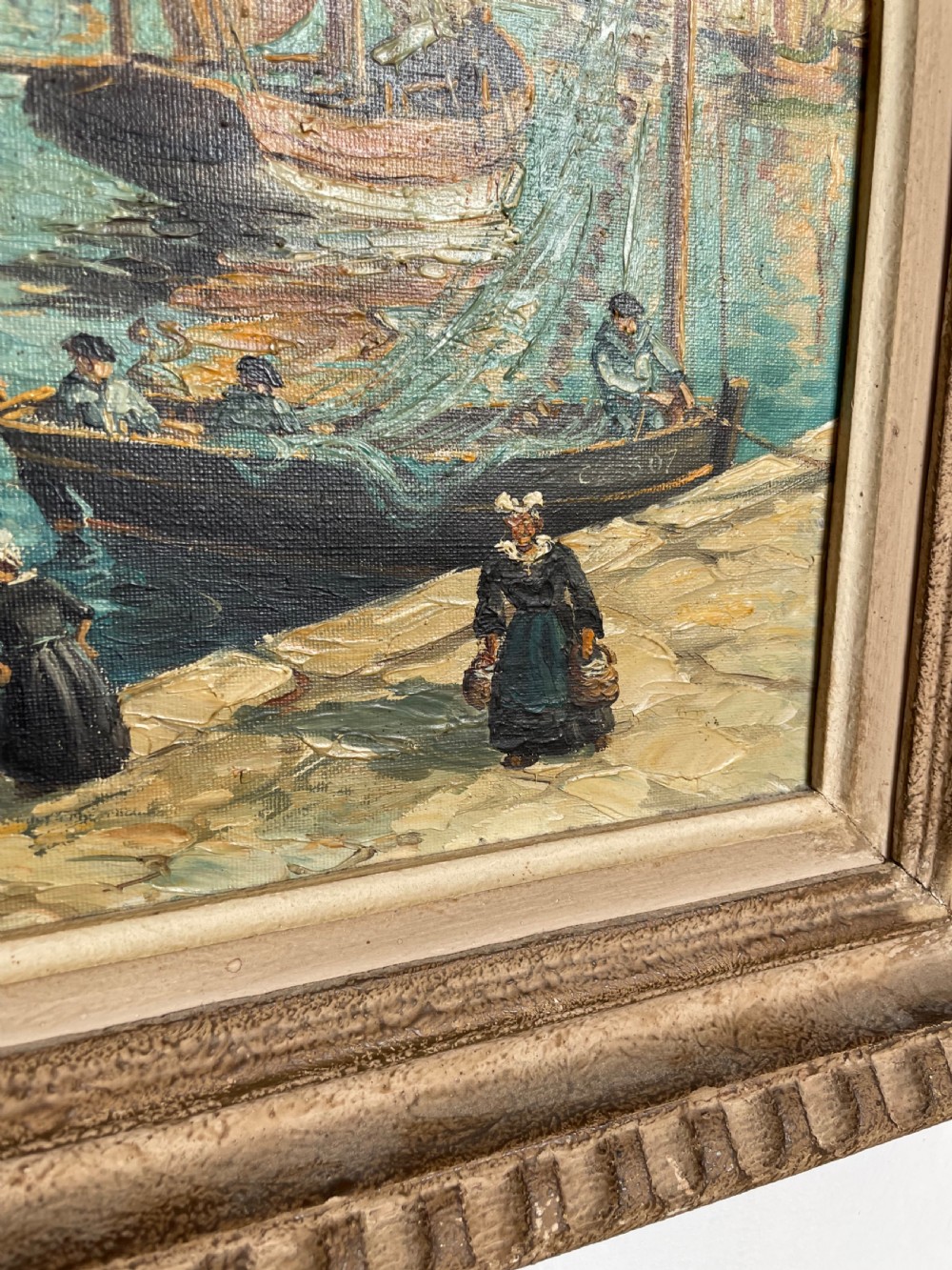 An oil painting on canvas depicting traditional fishing boats docked in a harbour alongside figures on a stone quay, enclosed in a carved wooden frame. View VI