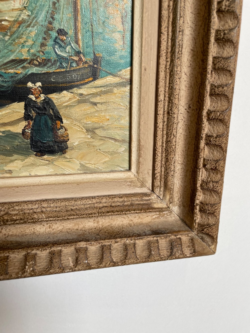 An oil painting on canvas depicting traditional fishing boats docked in a harbour alongside figures on a stone quay, enclosed in a carved wooden frame. View IX