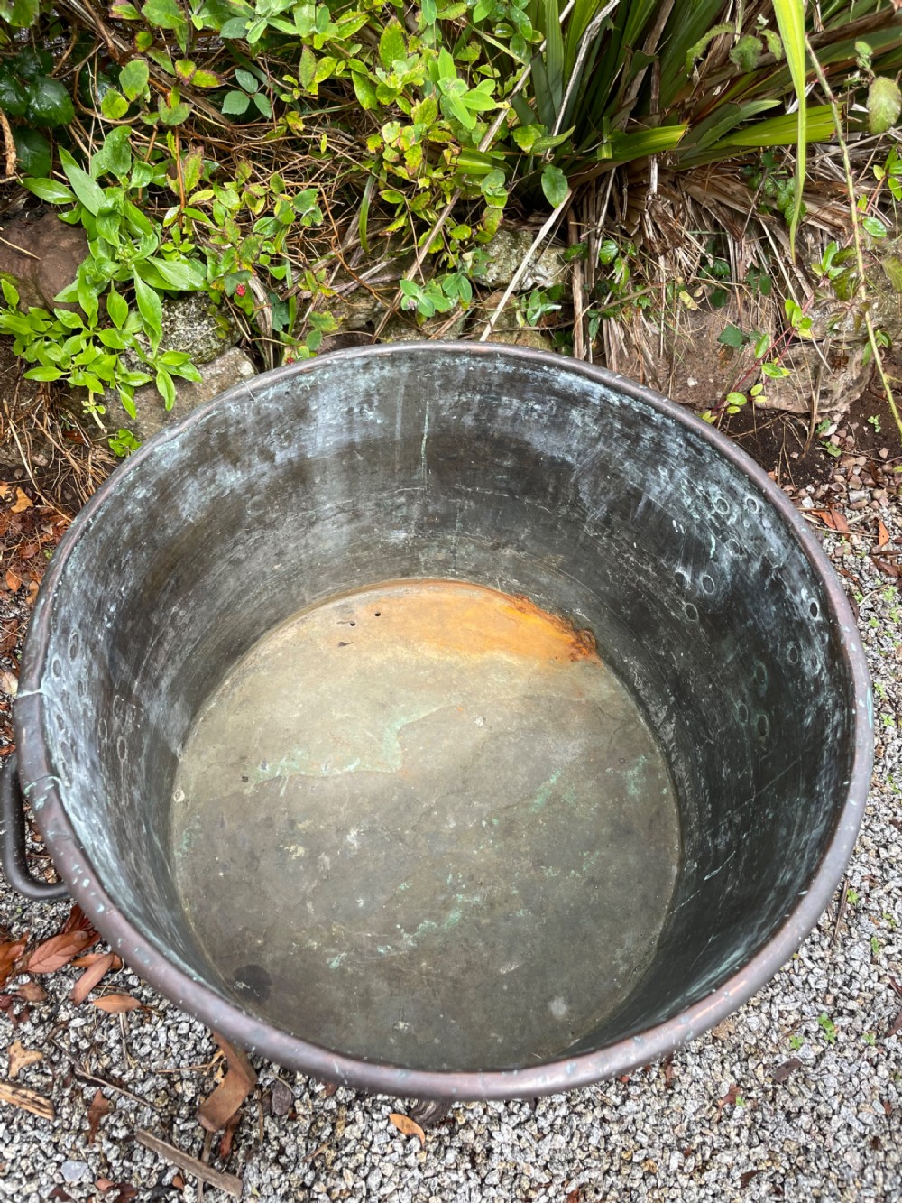 A large lidded copper log bin featuring riveted side handles, a flat lid with a central handle, and a raised iron support stand. View III