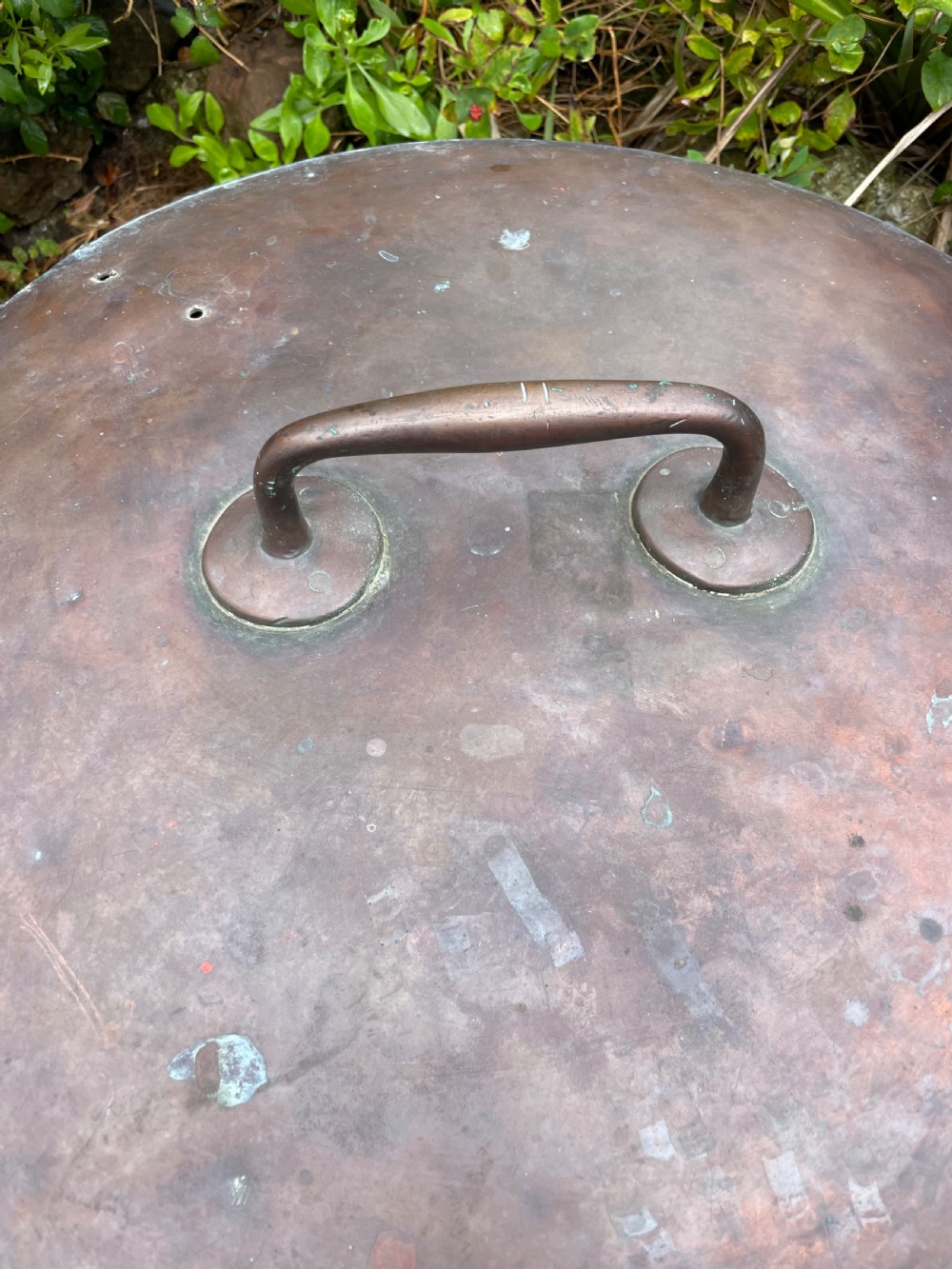 A large lidded copper log bin featuring riveted side handles, a flat lid with a central handle, and a raised iron support stand. View V