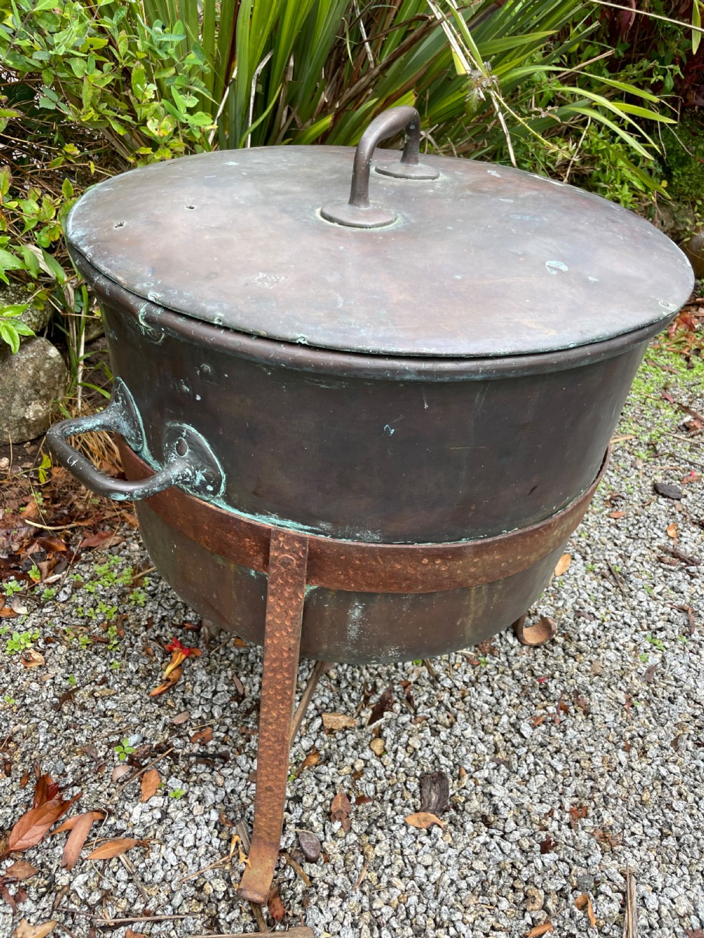 A large lidded copper log bin featuring riveted side handles, a flat lid with a central handle, and a raised iron support stand. View VII