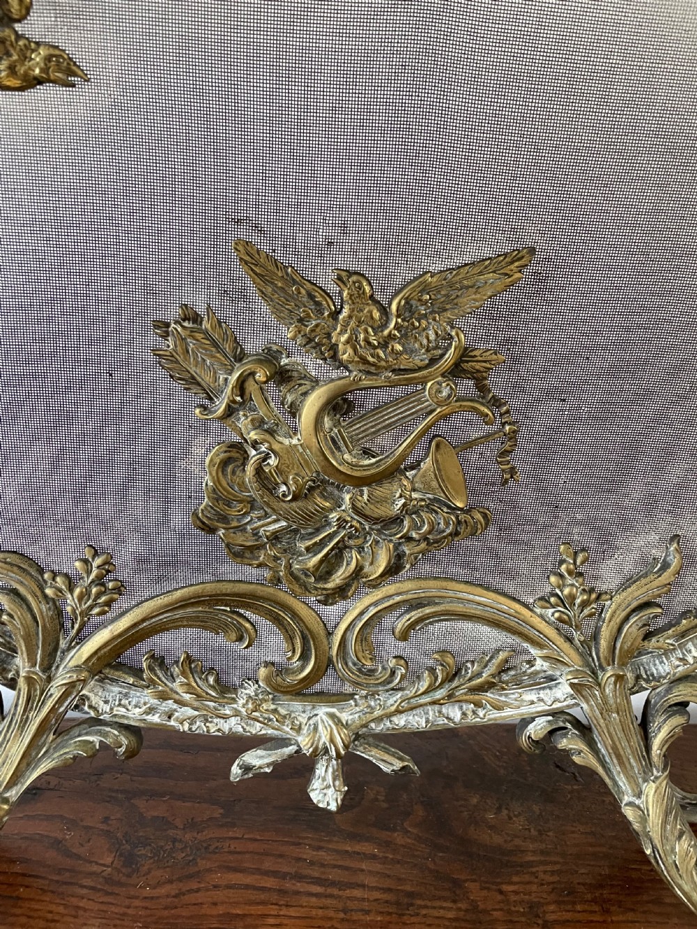 An ornate antique brass fire screen featuring pierced scrollwork, a central lyre and bird motif, and a wire mesh panel. View III