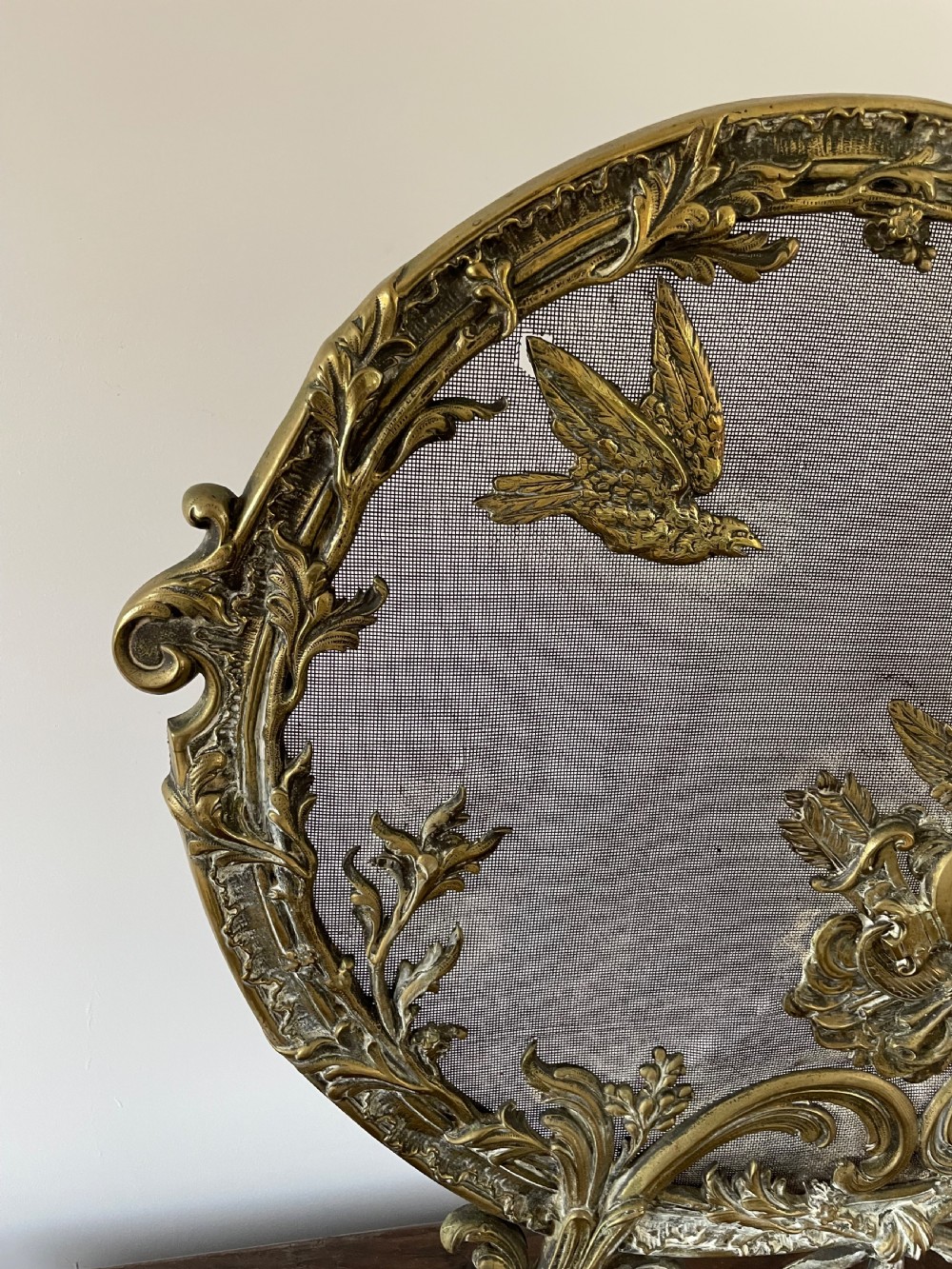 An ornate antique brass fire screen featuring pierced scrollwork, a central lyre and bird motif, and a wire mesh panel. View V