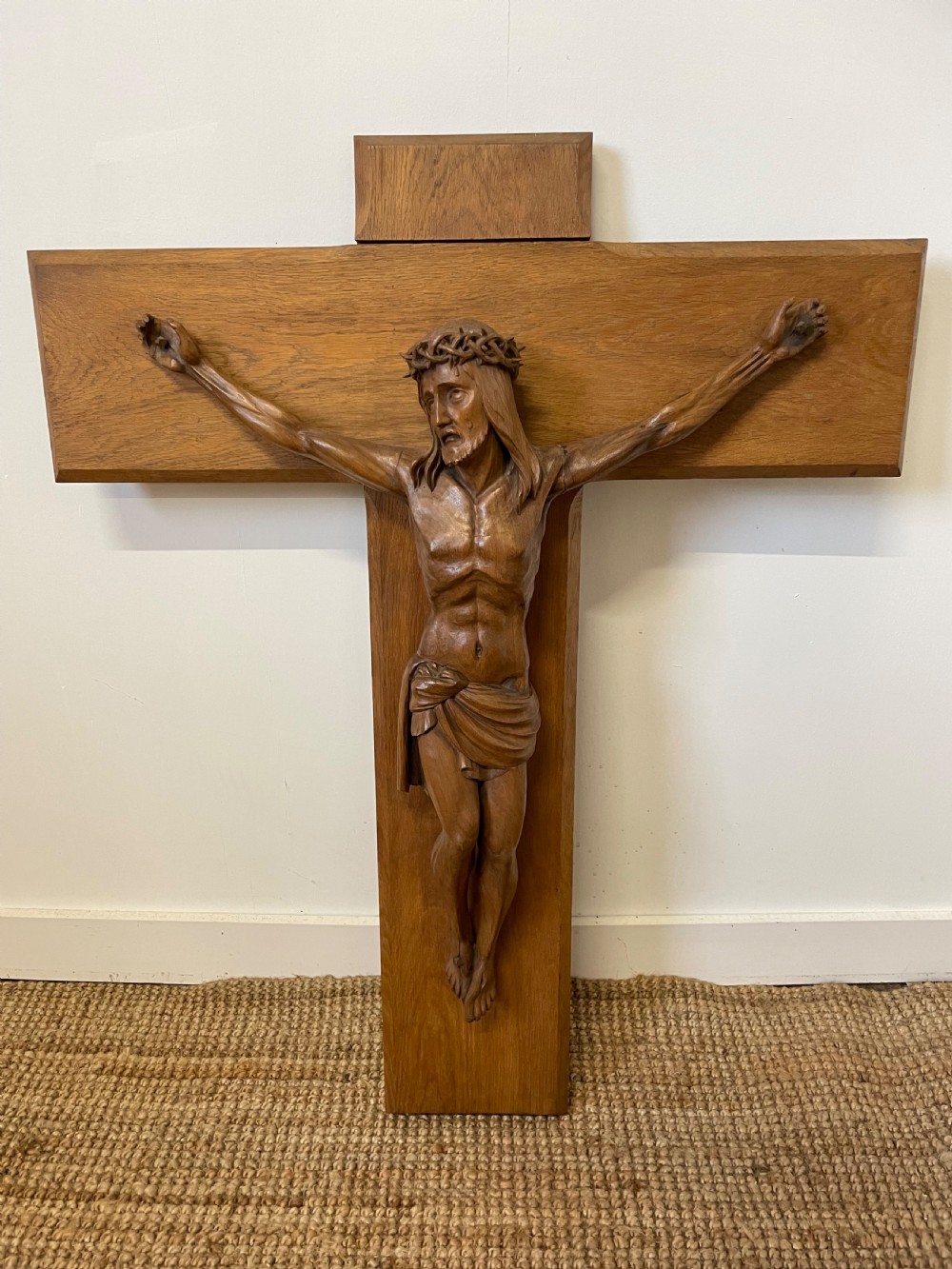A large Art Deco style carved oak crucifix featuring a detailed wooden figure of Jesus Christ mounted on a broad-armed cross.
