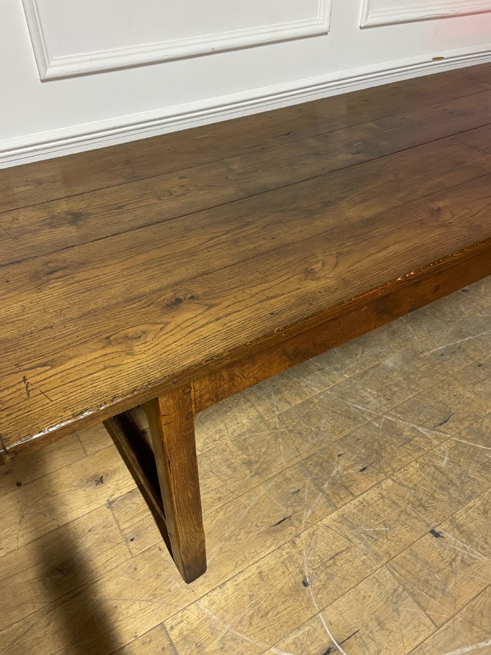 A long, antique oak farmhouse dining table featuring a planked timber top and straight wooden legs joined by side stretchers. View III