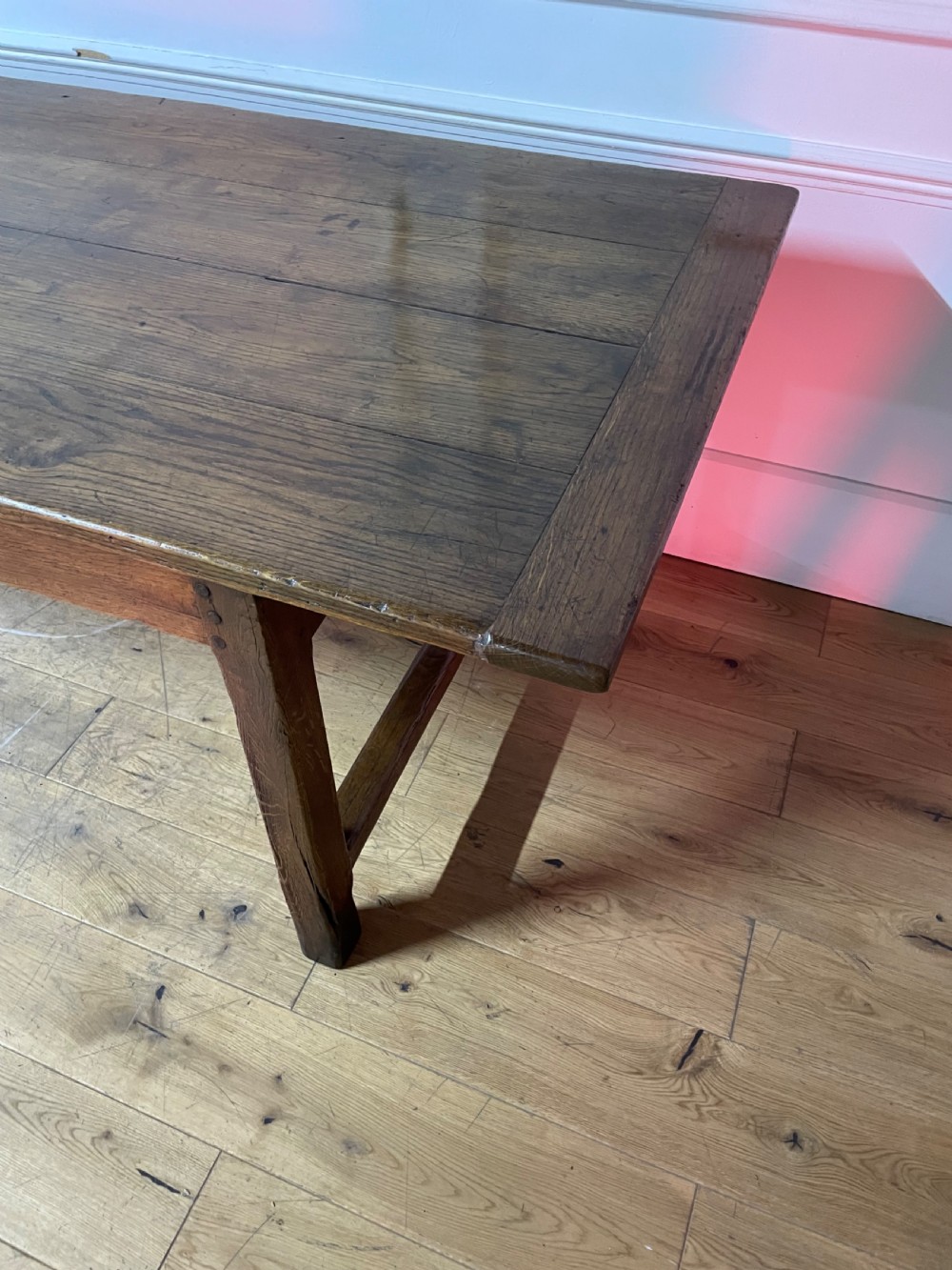 A long, antique oak farmhouse dining table featuring a planked timber top and straight wooden legs joined by side stretchers. View VII