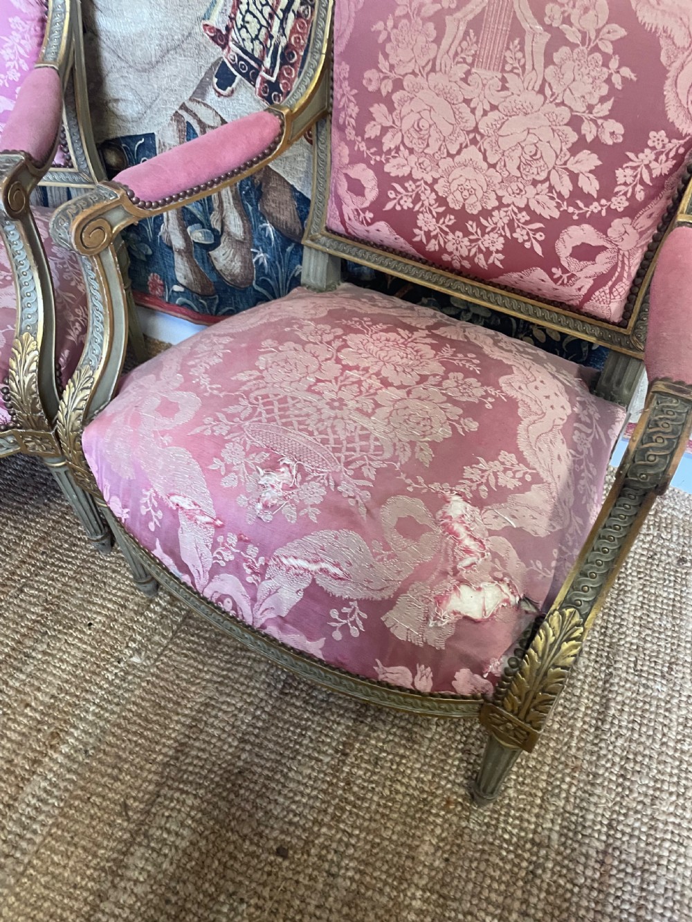 A pair of antique French fauteuils featuring carved gilt frames and pink patterned silk upholstery. View V
